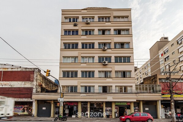 Un edificio de varios pisos con fachada plana, unidades de aire acondicionado y una tienda en la planta baja con un letrero.