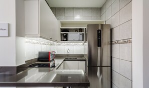 A modern kitchen with stainless steel appliances, a built-in microwave, and a coffee maker. - Practical Studio Near Farroupilha Park Hpn707 (Porto Alegre)