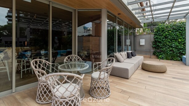 A modern outdoor patio with wicker furniture, a glass table, and a sofa. -  Luxury and Sophisticated Studio Apartment with Garage LBO203 (Porto Alegre)