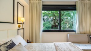 A hotel room with a bed, a sofa, a window with curtains, and a wall-mounted lamp. -  Luxury and Sophisticated Studio Apartment with Garage LBO203 (Porto Alegre)