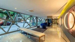 A modern hotel lobby with a bench, a blue sofa, and a large window with a view of the street. -  Luxury and Sophisticated Studio Apartment with Garage LBO203 (Porto Alegre)