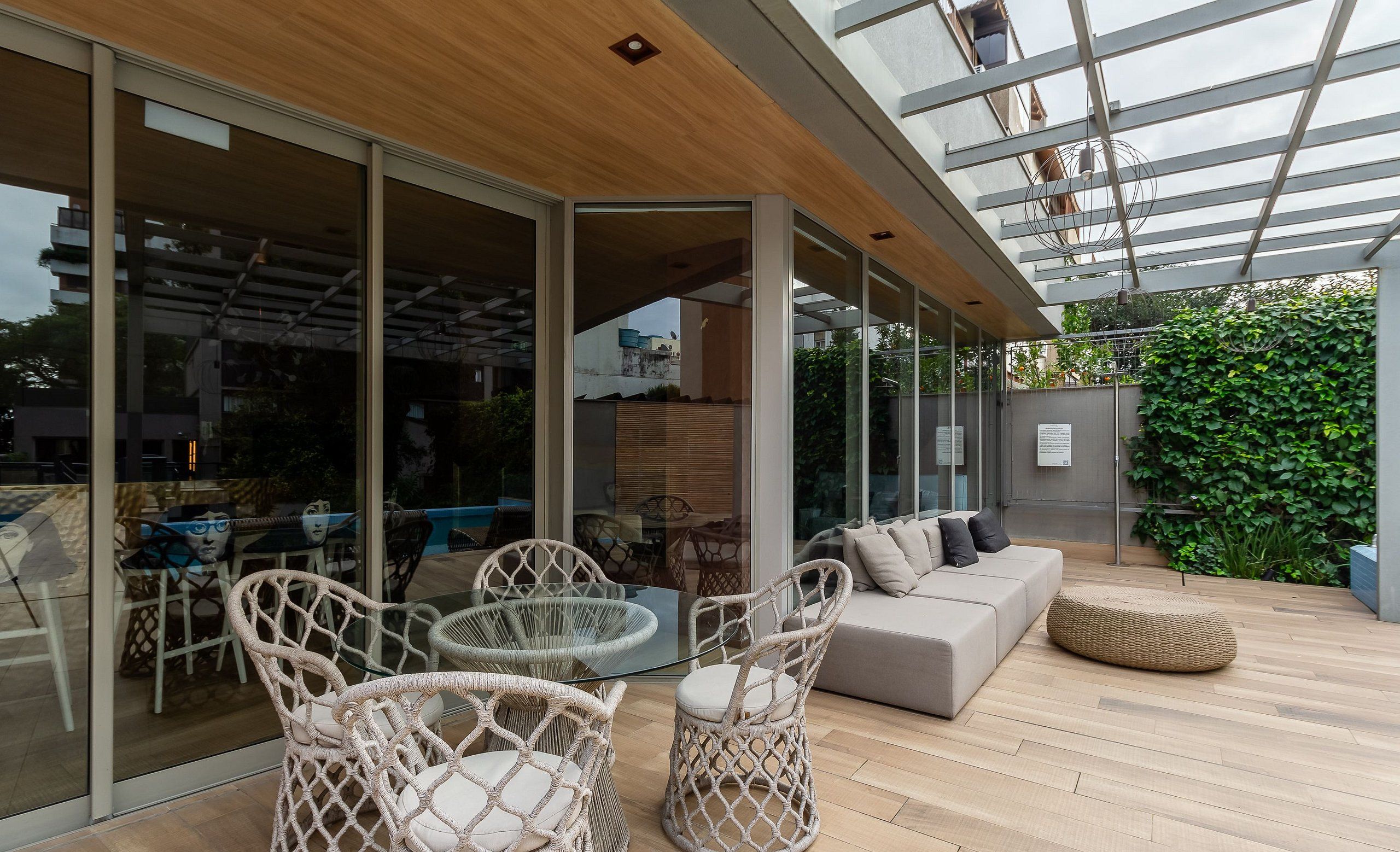 Un patio moderno al aire libre con mobiliario de mimbre, una mesa de vidrio y un sofá.