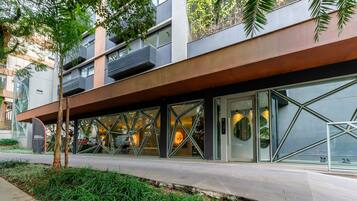 Un edificio moderno con fachada de vidrio, zona de estar al aire libre y una combinación de espacios verdes y elementos arquitectónicos.