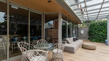 Een moderne terras met rieten meubels, een glazen tafel en een bank.