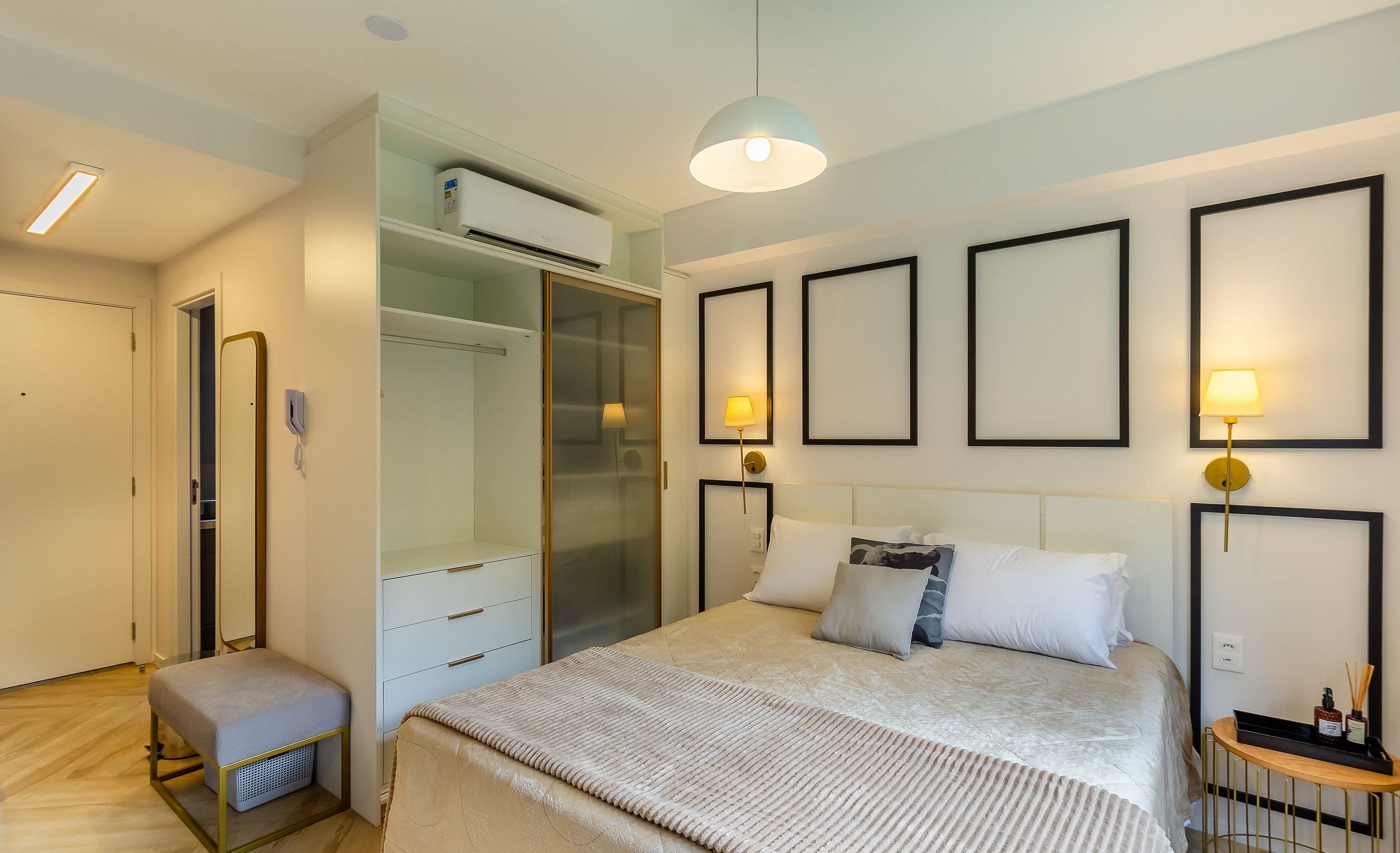 Un dormitorio moderno con cama, mesitas de noche, armario y una pequeña zona de estar.