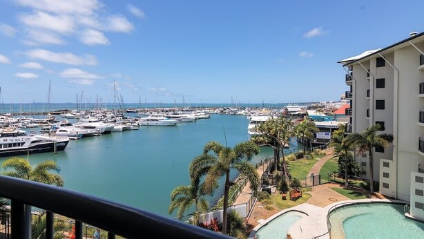 A marina with numerous boats, a swimming pool, and a building with balconies overlooking the water.