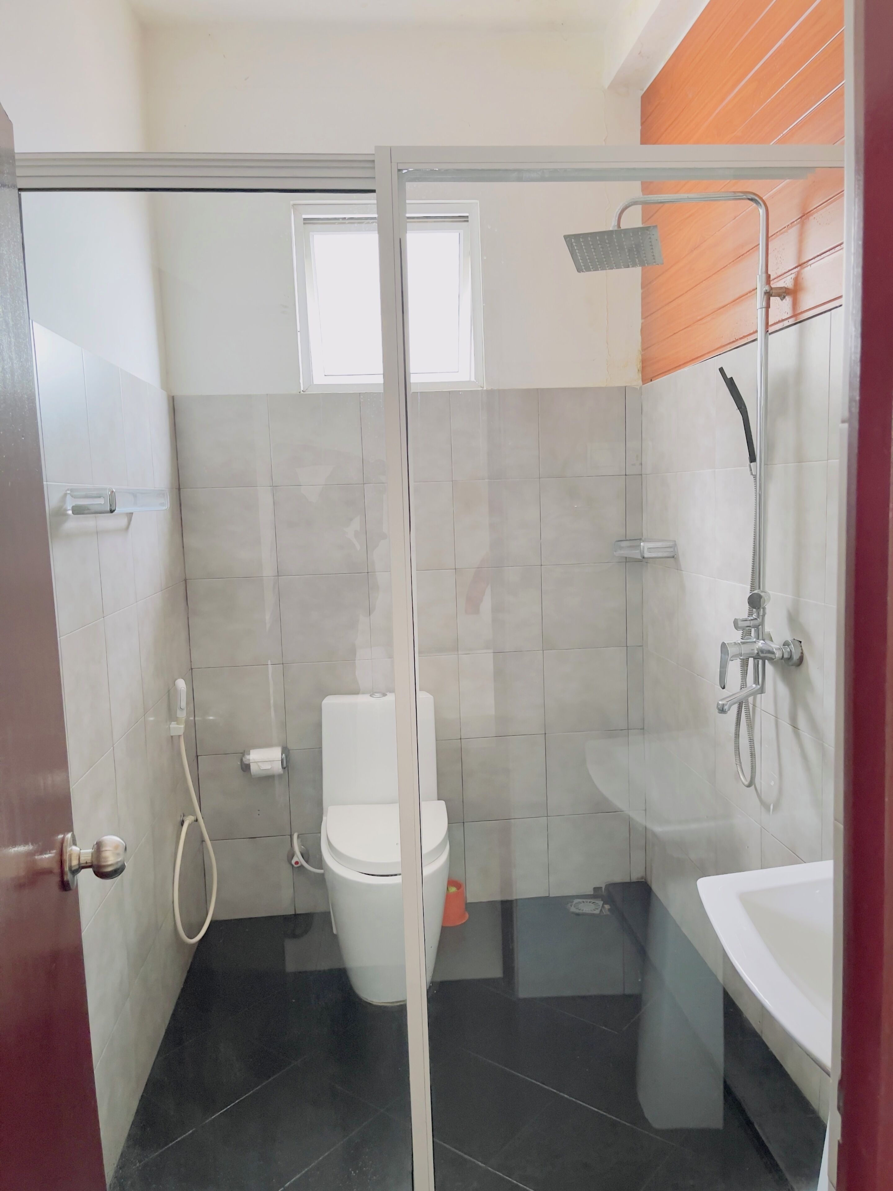 A modern bathroom with a glass-enclosed shower, a toilet, and a bathtub.