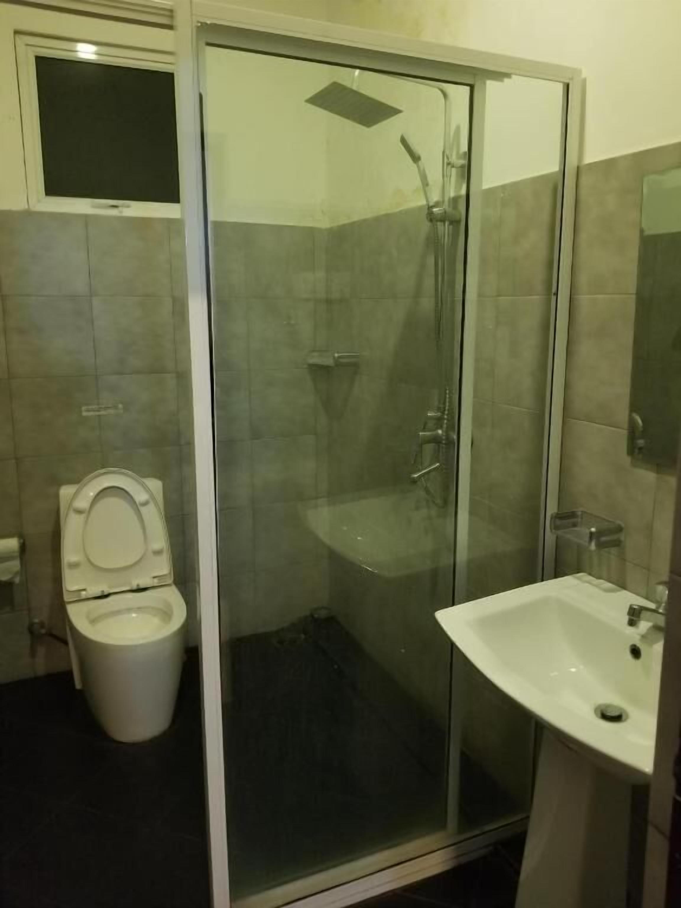A bathroom with a glass-enclosed shower, a toilet, and a sink.