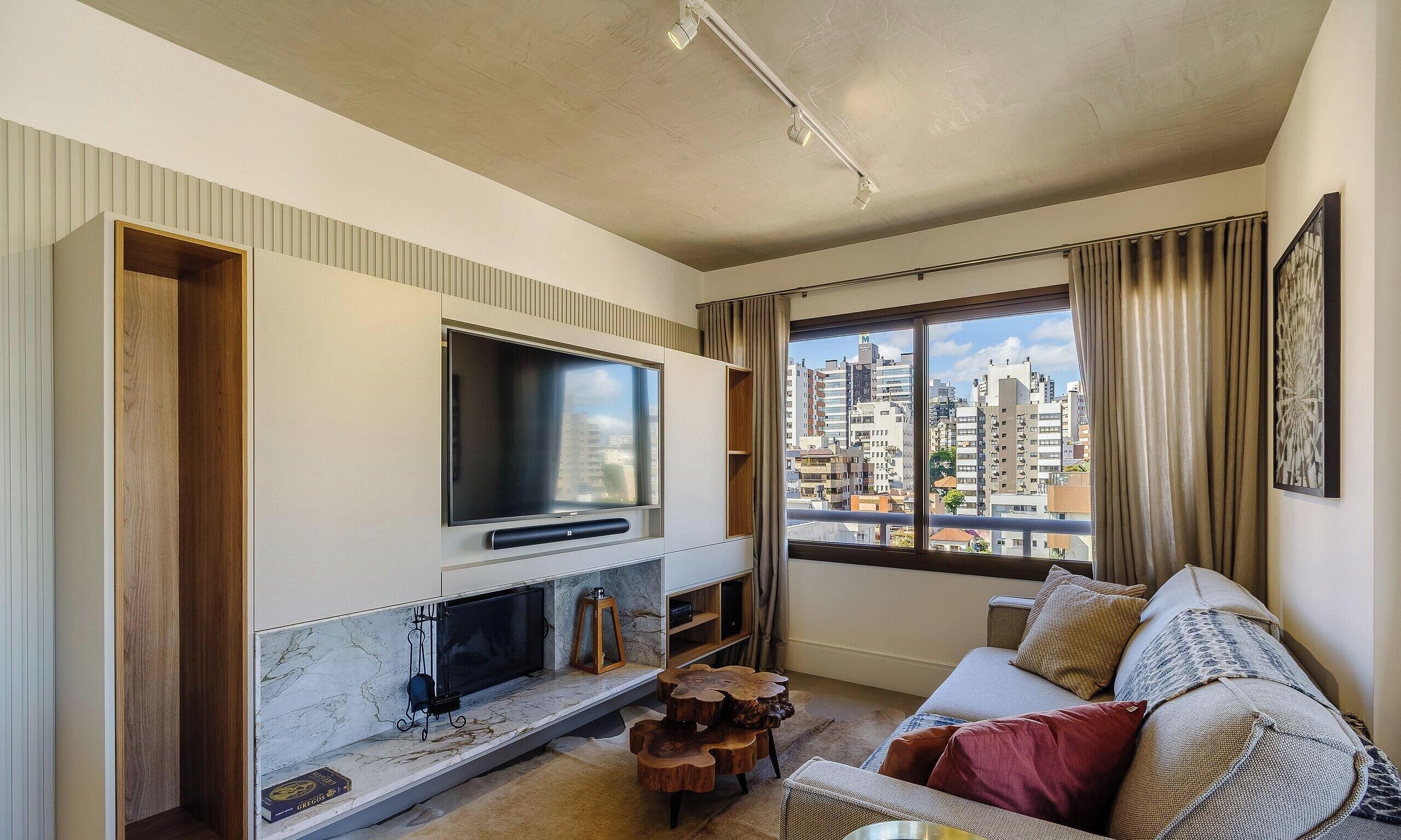 A modern living room with a large flat-screen TV, a fireplace, and a sofa with cushions.