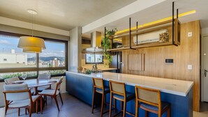 A modern kitchen with a large island, bar stools, and a dining area with a table and chairs. - Comfort and a Beautiful View! Pgr1101 (Porto Alegre)