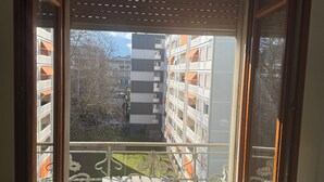 Un balcón con barandilla metálica y vistas a edificios cercanos.