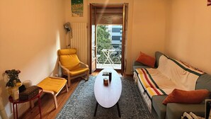 Una sala de estar con sofá, sillón amarillo, mesa de centro y alfombra estampada.