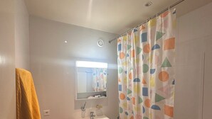 Un baño con lavamanos blanco, espejo y cortina de ducha con diseño geométrico.