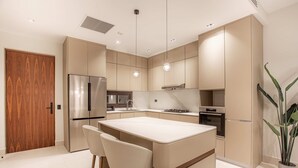 Een moderne keuken met een centraal eiland, roestvrijstalen apparatuur en een houten deur.