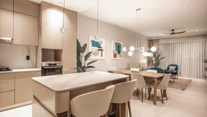 Een moderne keuken met een marmeren aanrechtblad, roestvrijstalen apparatuur en hanglampen.