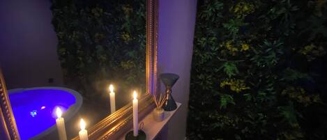 A bathroom with a bathtub, candles, and a mirror.