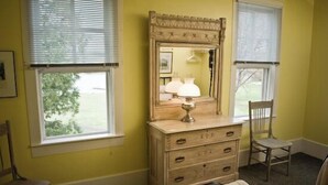 A room with a wooden dresser, a mirror, and two chairs.