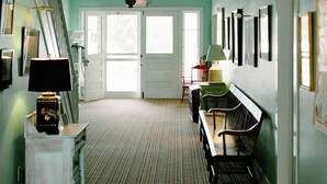 A hallway with a striped carpet, a bench, a lamp, and a staircase.