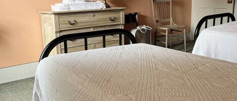A hotel room with a bed, a dresser, a chair, and a mirror on the wall.