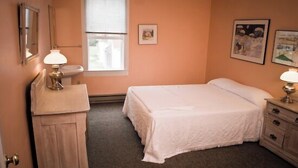 Une chambre à coucher avec un lit, une commode, un miroir et une fenêtre.