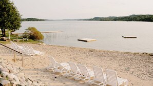 A beach with white lounge chairs and a wooden dock extending into calm water. - Fountain Point - Hotel Room 14 (Lake Leelanau)