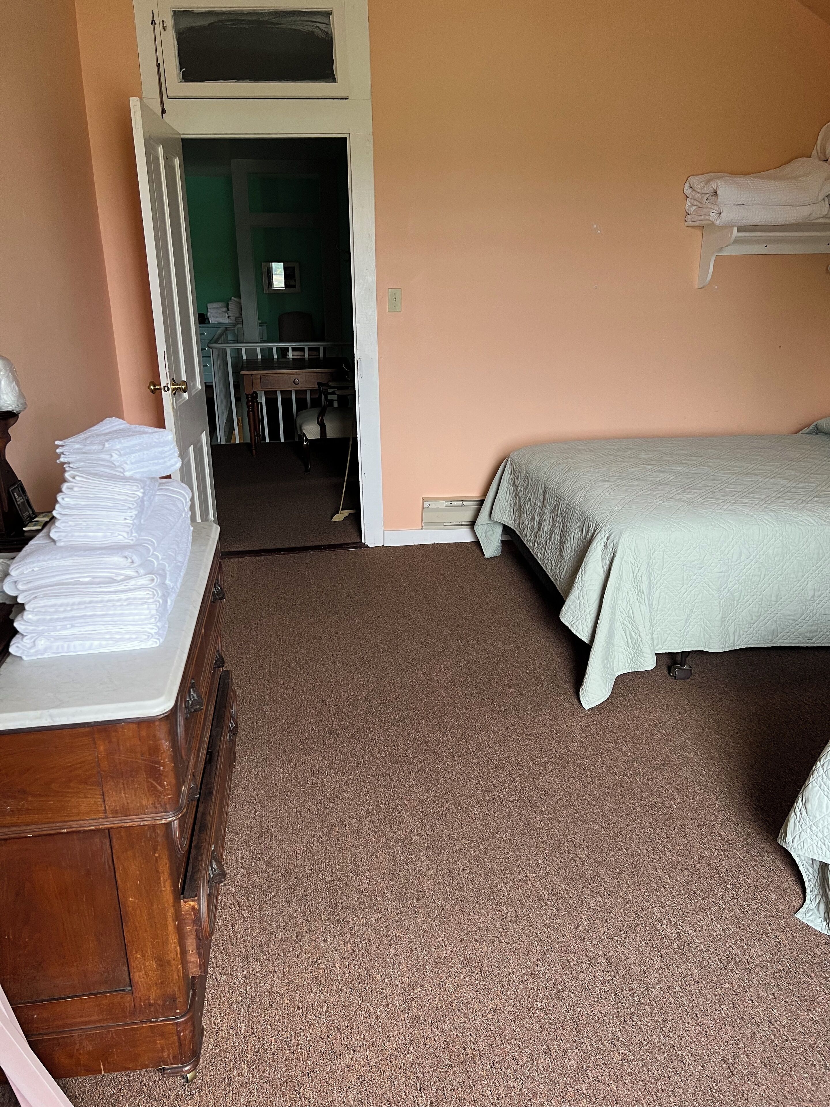 Quarto com uma cama, uma cômoda e uma porta que dá para um banheiro.