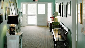 A hallway with a striped carpet, a bench, a lamp, and a staircase. - Fountain Point - Hotel Room 15 (Lake Leelanau)