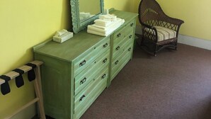 A room with a green dresser, a wicker chair, and a mirror. - Fountain Point - Hotel Room 17 (Lake Leelanau)
