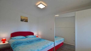 A bedroom with a bed, bedside lamps, a mirror, and a painting on the wall.