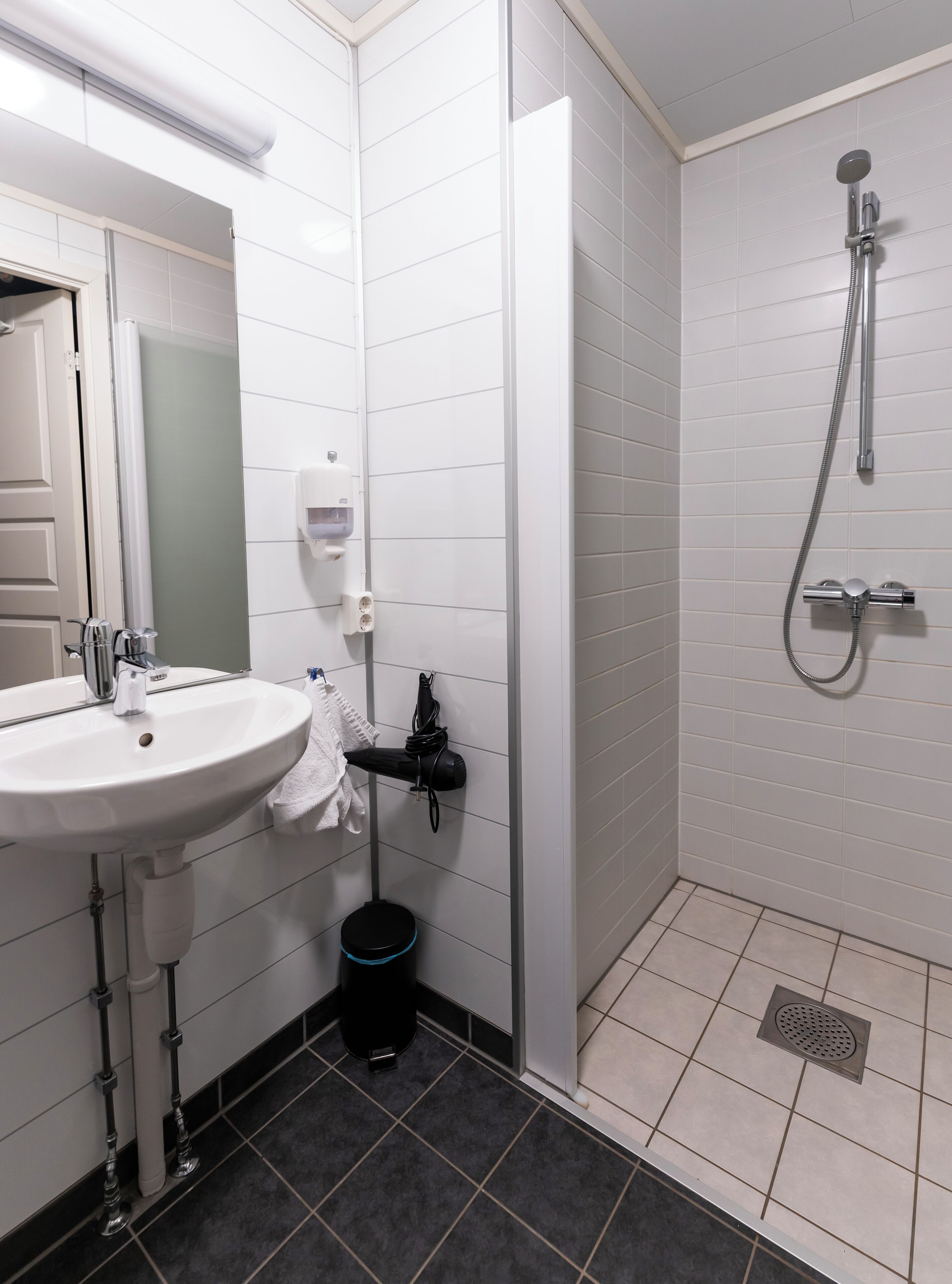 A modern bathroom with a white sink, mirror, and shower.