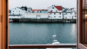 Vista desde una ventana con vista al frente marítimo, edificios y un barco amarrado.