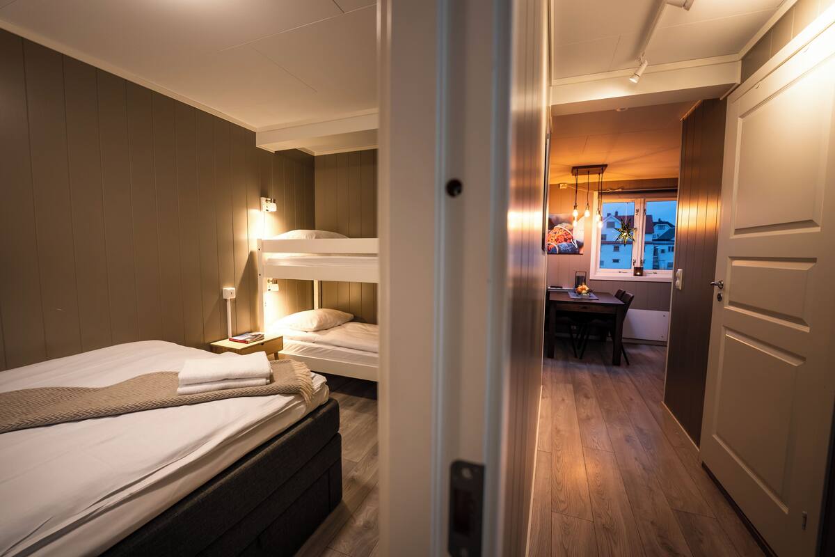A hotel room with a bed, bedside table, and a desk with a chair.