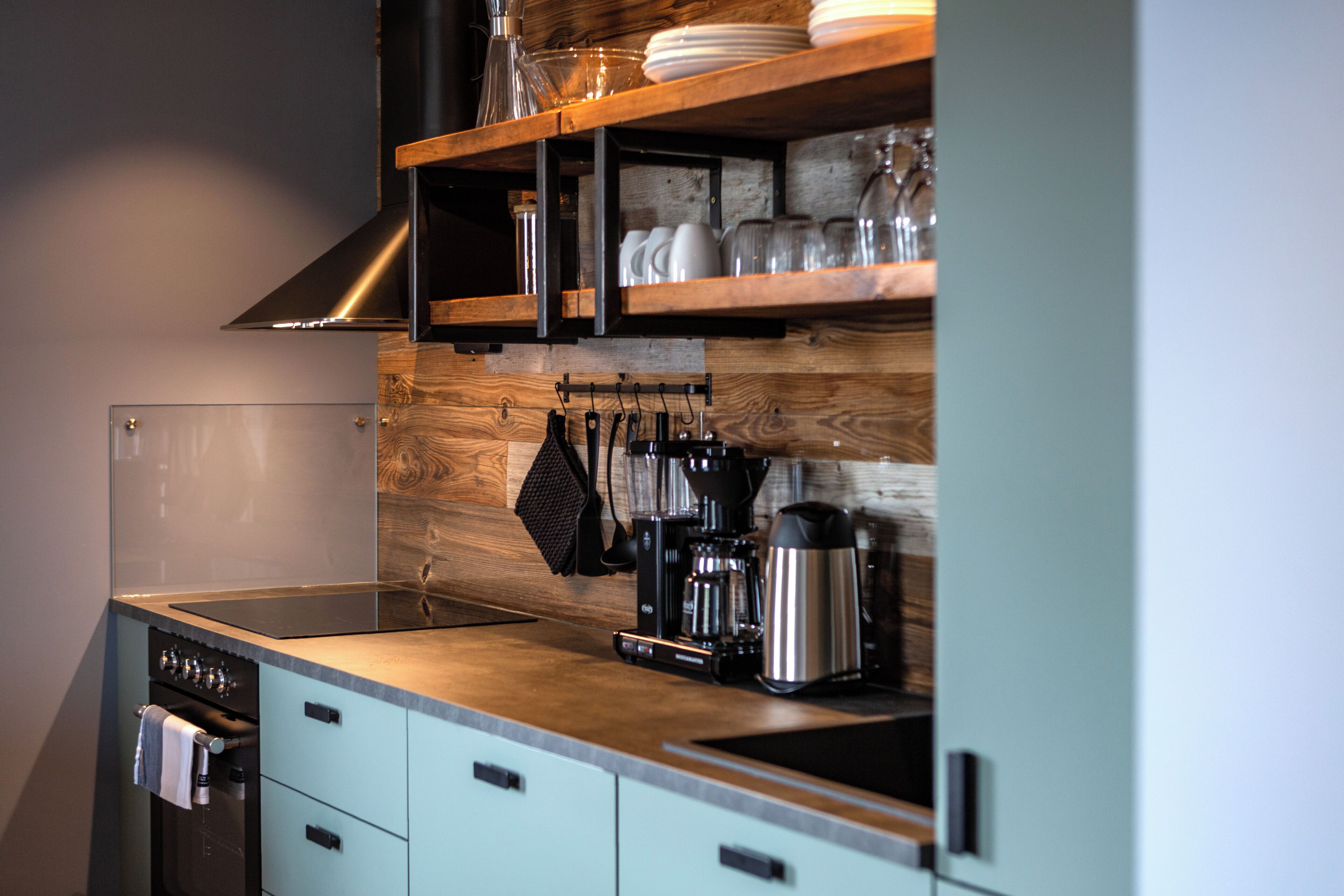 A modern kitchen with a wooden backsplash, stainless steel appliances, and a built-in oven.