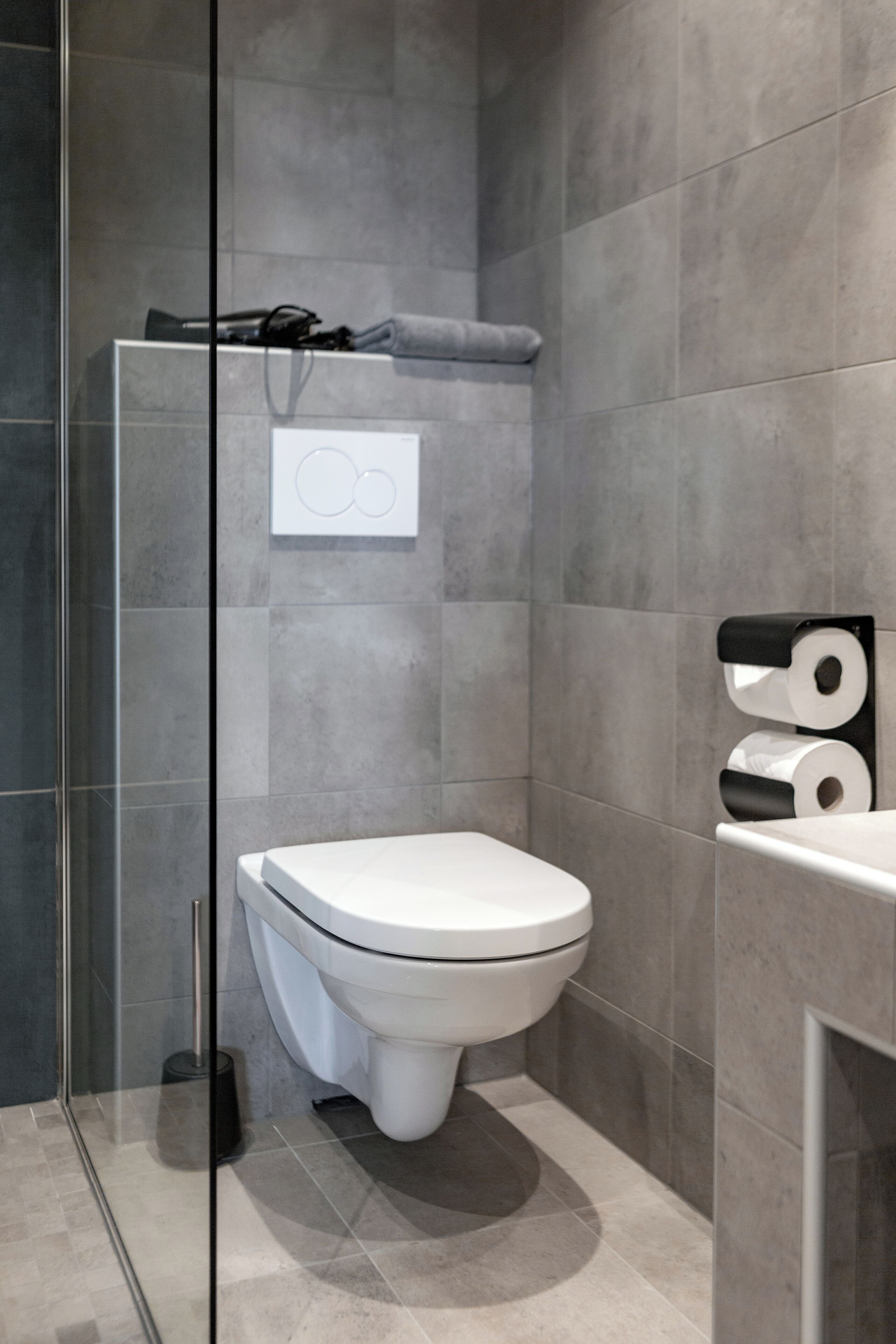 Un baño moderno con inodoro, cabina de ducha de vidrio y un perchero para toallas.
