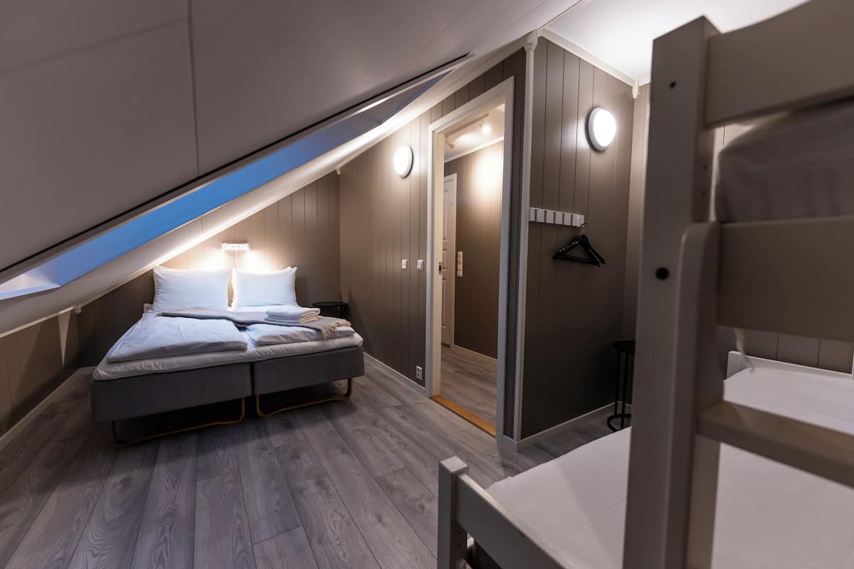 A bedroom with a loft bed, a walk-in closet, and a small table.