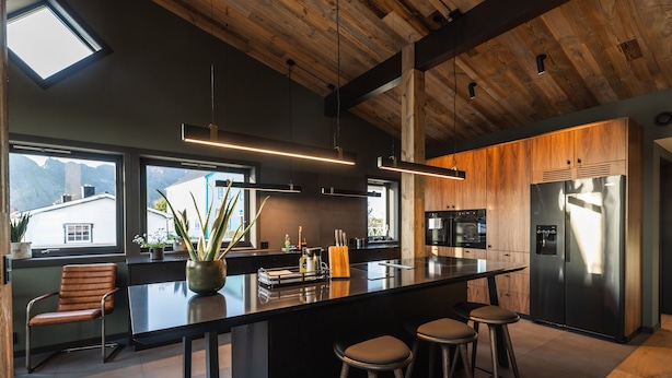 Una cocina moderna con una isla grande, techo de madera y amplias ventanas con vistas a la montaña.