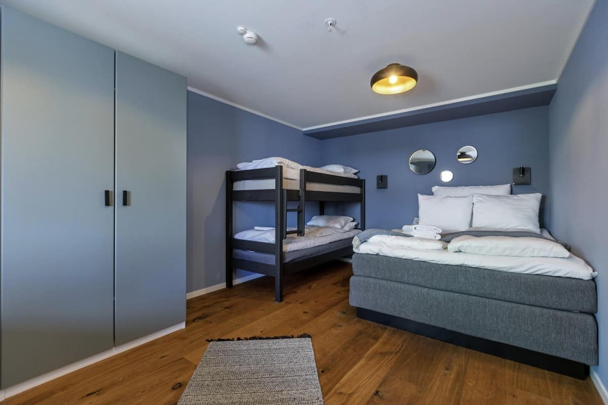 A bedroom with a bunk bed, a sofa bed, and a wardrobe.