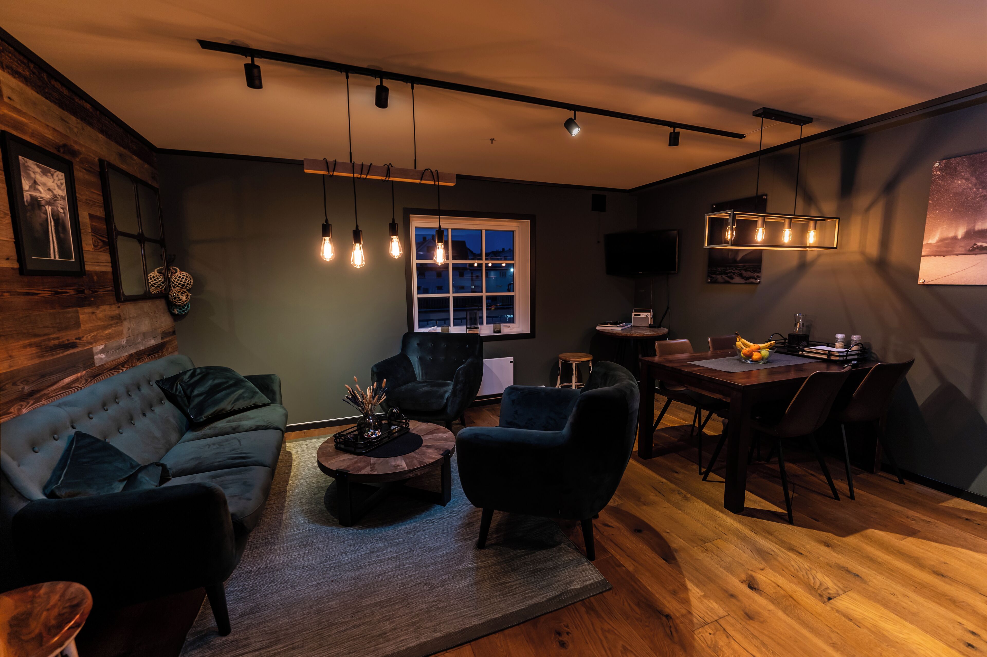 A modern living room with a sofa, armchairs, a coffee table, and a dining area with a table and chairs.
