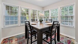 A dining room with a large table, four chairs, and a window with blinds. - Gainesville Hideaway (Gainesville)