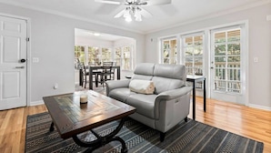 A spacious living room with a gray leather sofa, a wooden coffee table, and a ceiling fan. - Gainesville Hideaway (Gainesville)