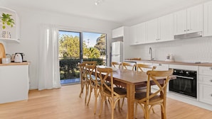 Una cocina moderna con armarios blancos, una mesa de comedor de madera y sillas.