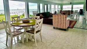 A spacious living area with a view of the water, a dining table with chairs, and a sofa. - Orange Bay Retreat - Amazing View (Fort Myers Beach)