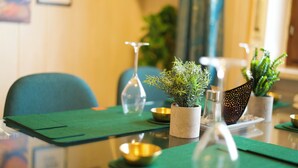 A dining table with green placemats, gold bowls, and potted plants. - Stylish and artistic apartment with 400 sqm garden & massage and Ayurveda (Grainet)