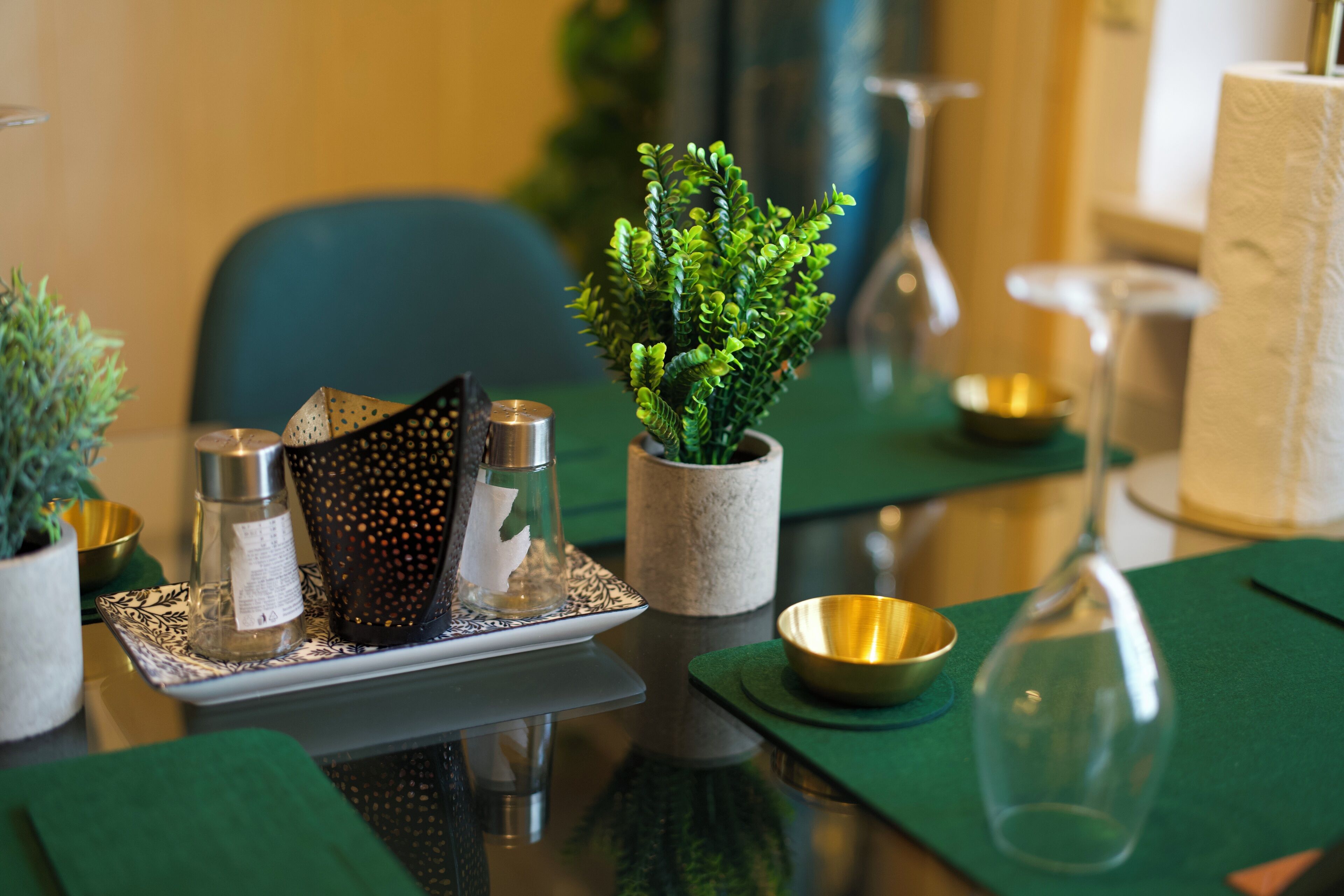 A dining table with a potted plant, a glass pitcher, and a candle holder.