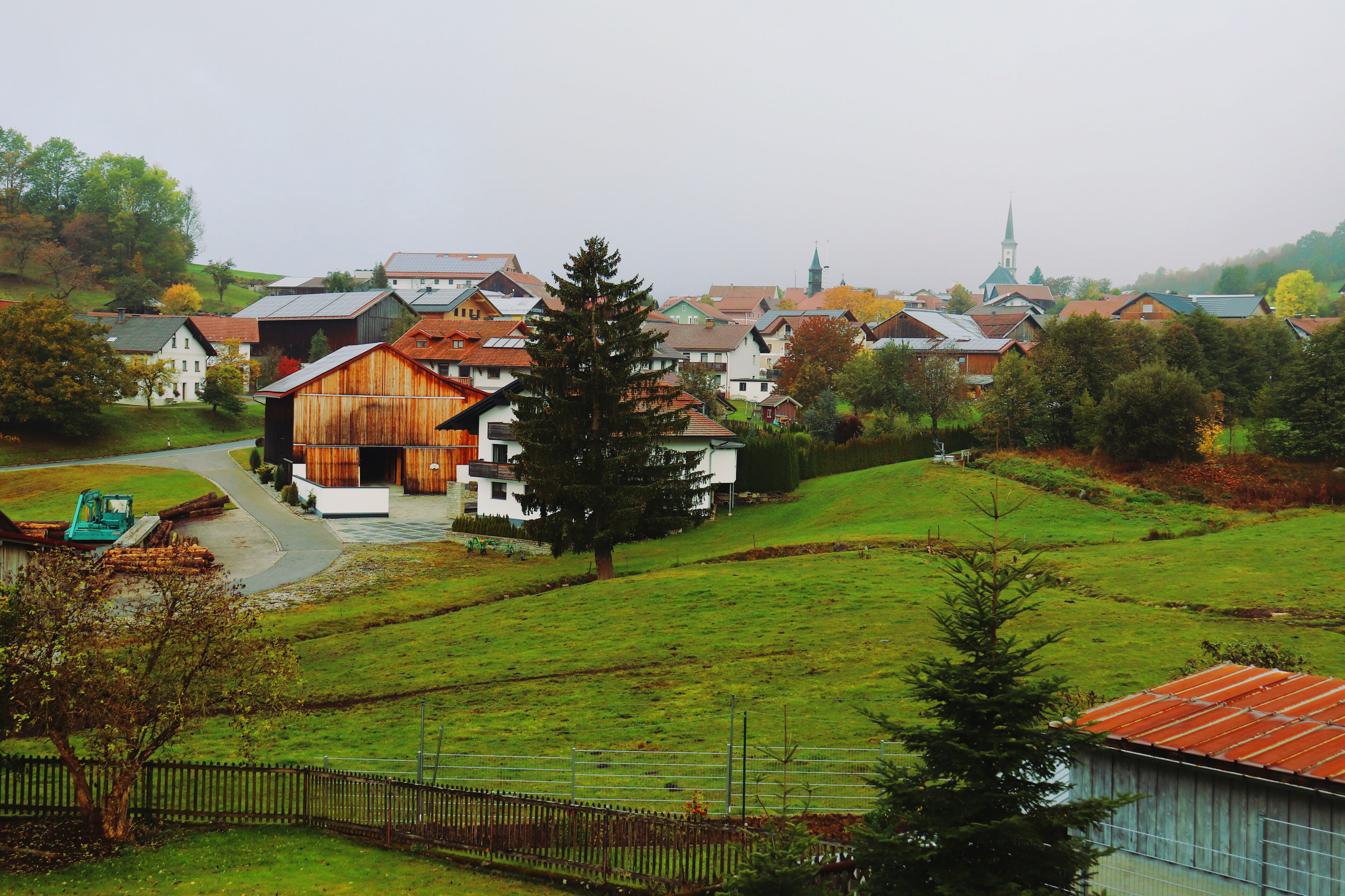 A rural village with traditional houses, a church, and a large wooden barn.