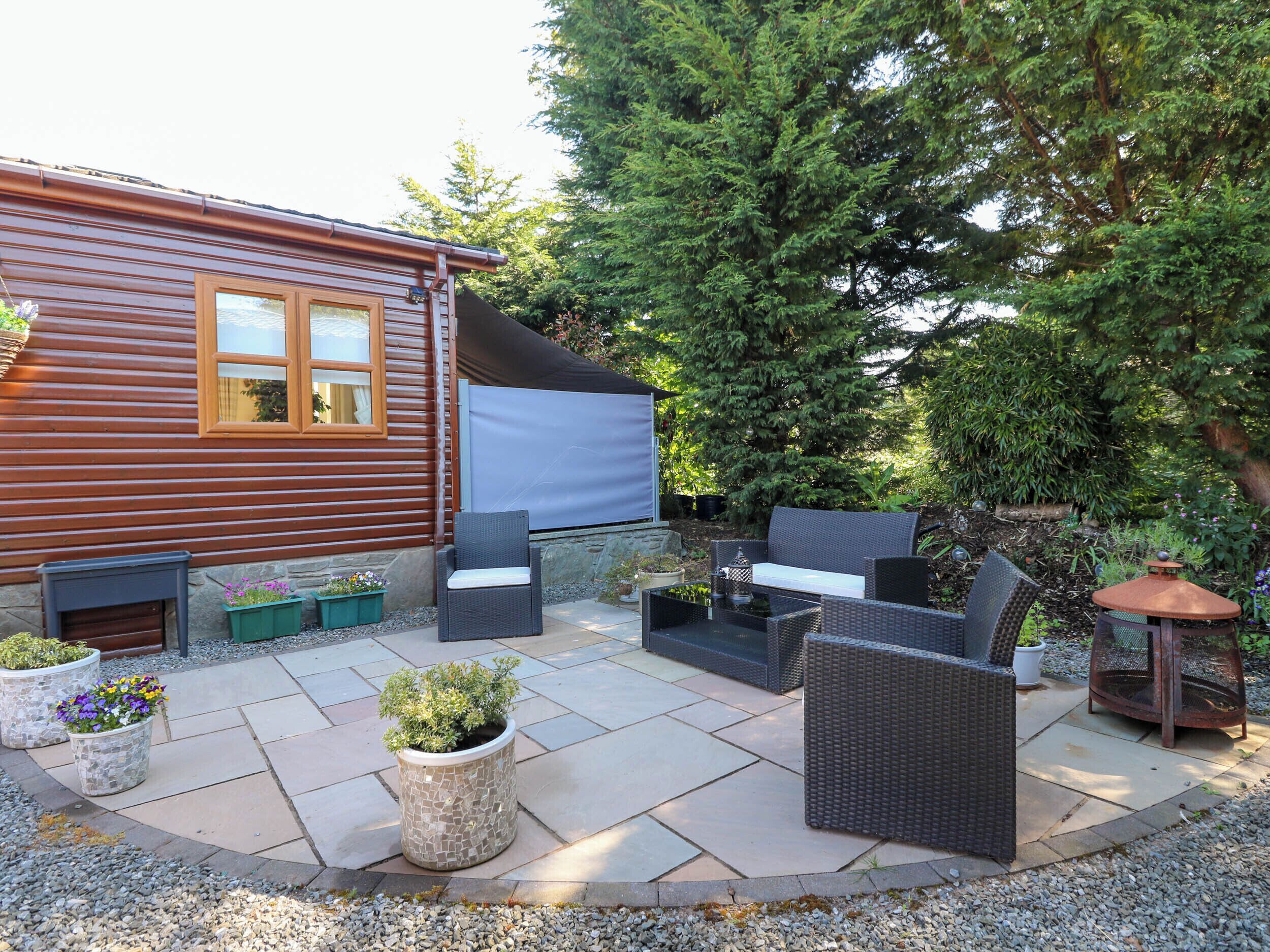 A patio with wicker furniture, a stone fire pit, and potted plants.