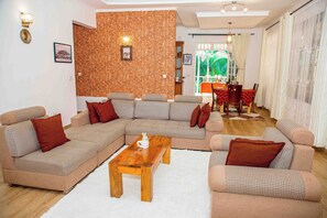 Un salon avec un canapĂ© dâangle, une table basse en bois et un mur dĂ©coratif en briques.