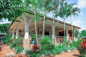 A covered outdoor area with a brick wall, palm trees, and various plants.