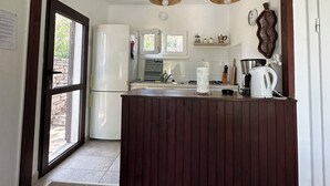 Une cuisine dotée d’un îlot central en bois, d’appareils électroménagers blancs et de luminaires suspendus.