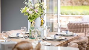 A dining table set with plates, glasses, and a vase of flowers. - Lavender Cottage (Cheltenham)